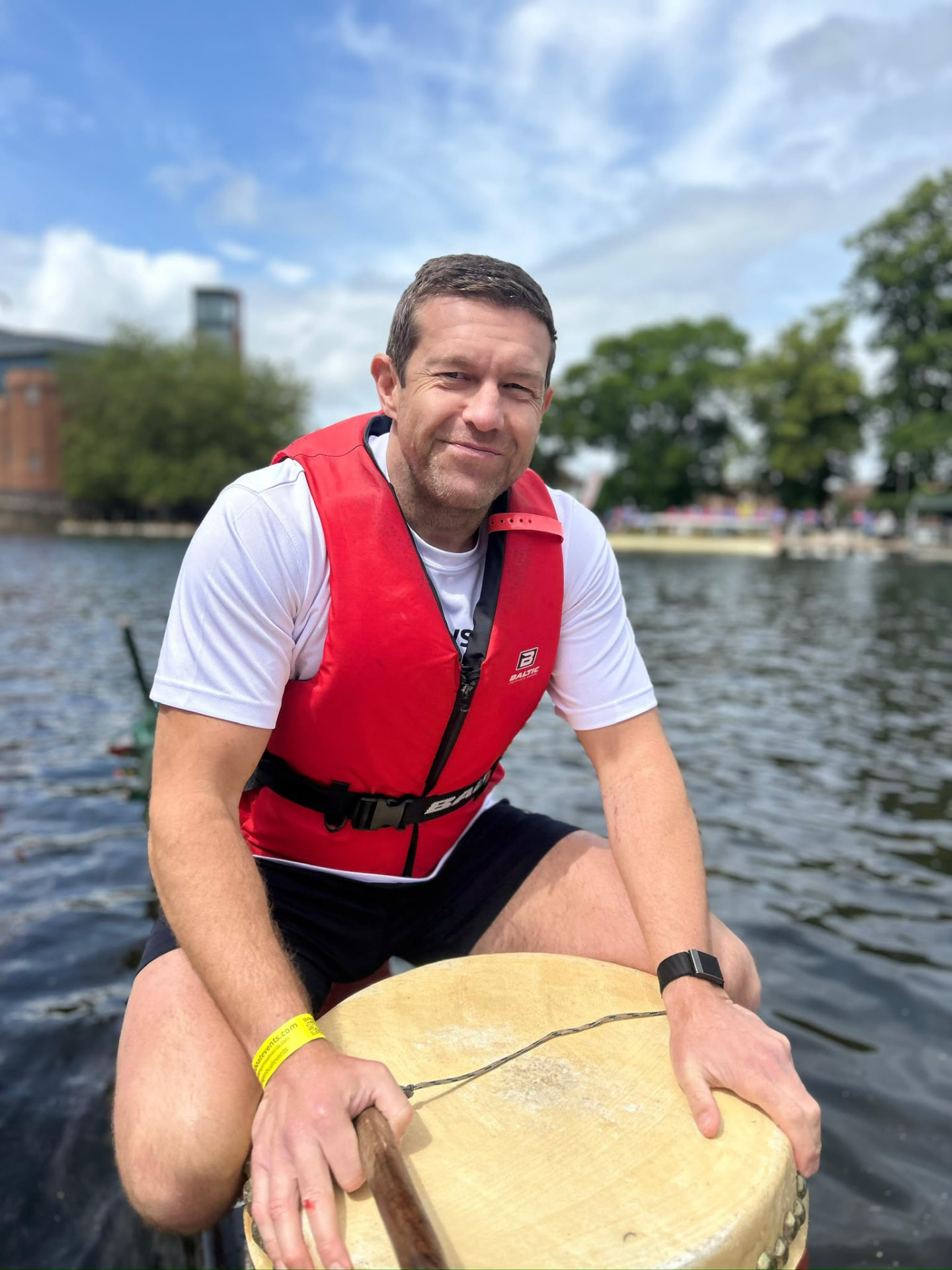 A member smiling at the drum at the front of the dragon boat