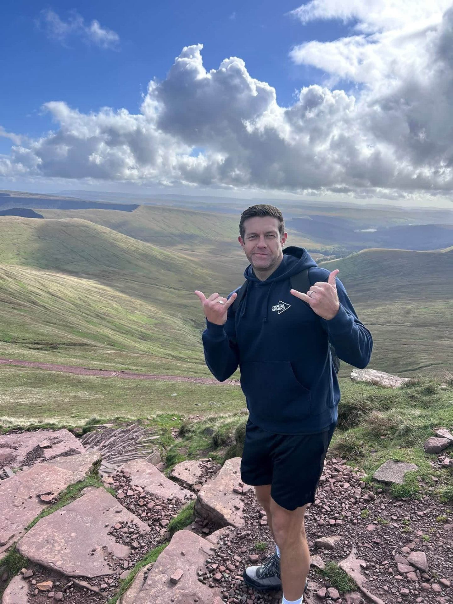 A member on the rocky summit path, grinning at the view