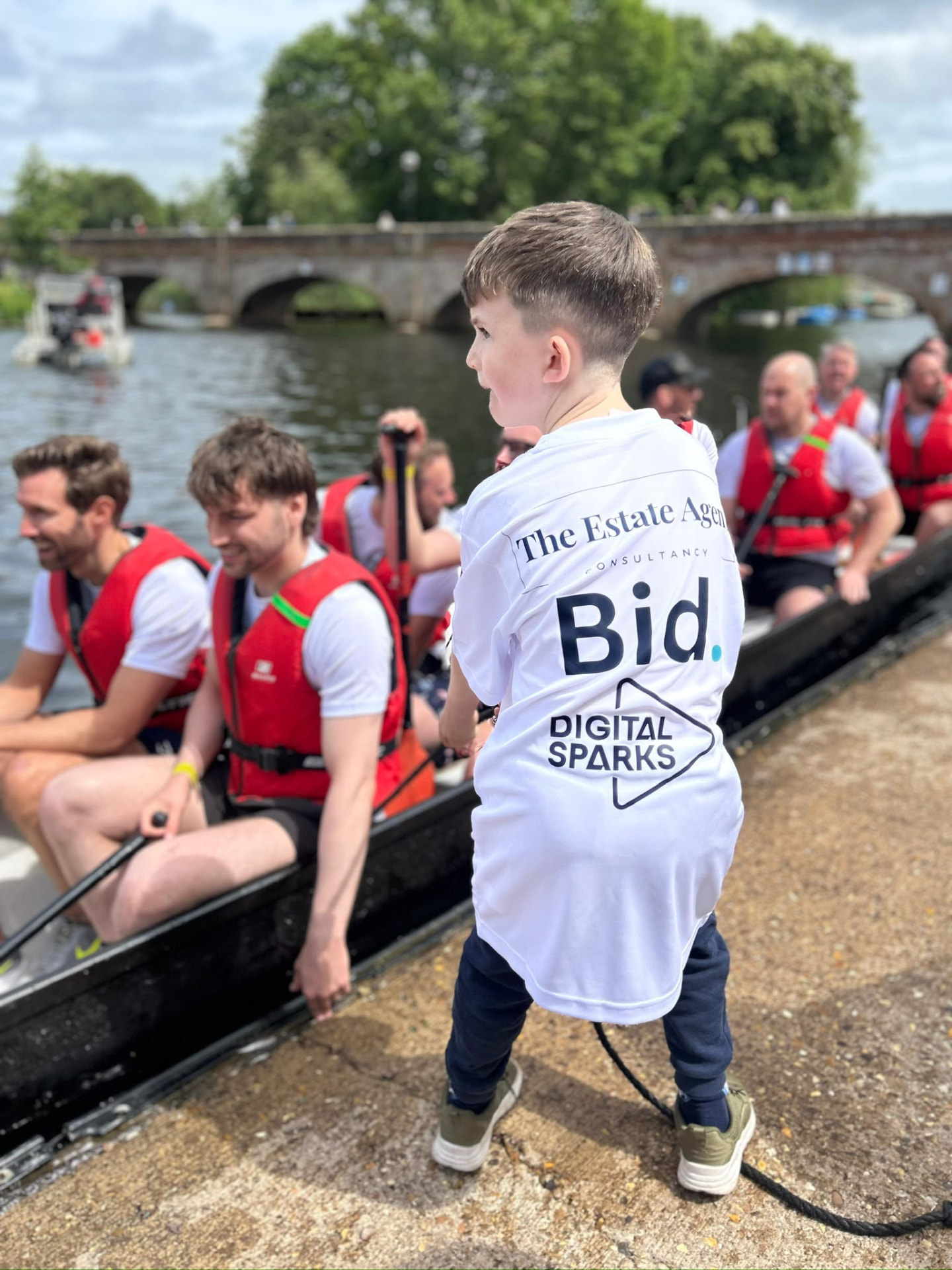 The TBC crew sitting in a dragon boat with their paddles, ready to push off from the riverbank