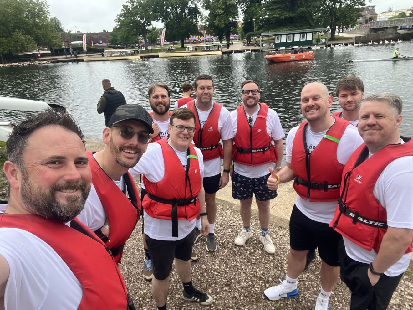 The crew in their life jackets posing together on the riverbank between races