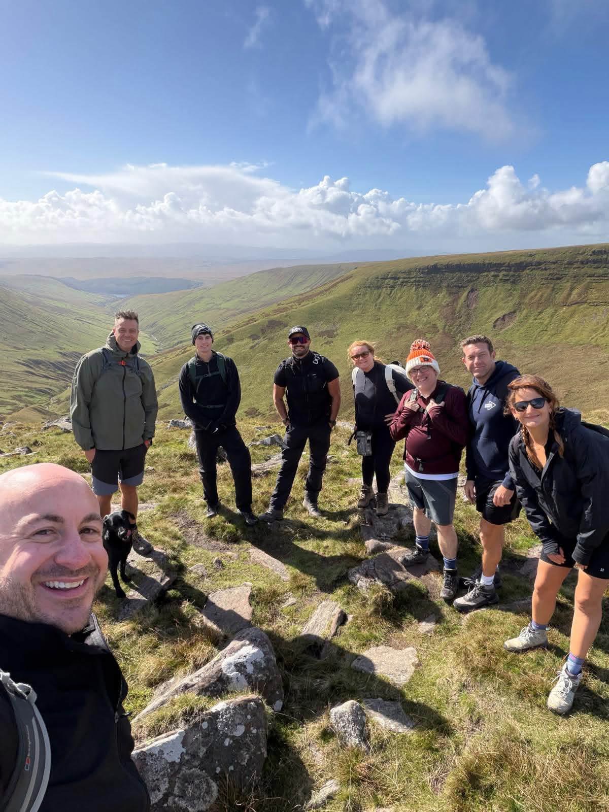 Members taking a selfie together on a rocky ridge during a group walk